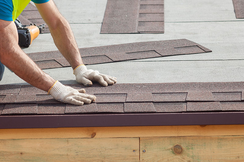 Roofing Contractor Laying Asphalt Shingles During A Roof Replacement